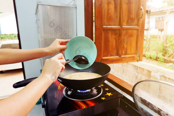 女人的手是用平底锅做饭、用<strong>勺子</strong>搅拌、用<strong>勺子</strong>铲