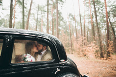 时尚爱婚礼情侣接吻和拥抱在一片松树林附近复古车
