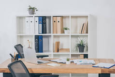 桌子在办公室与笔记本电脑, 文件, 椅子和书柜的文件夹在后台