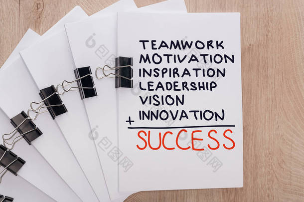 白纸片的顶部视图用粘合剂夹和团队合作、动机、灵感、<strong>领导力</strong>、远见、创新、木制桌子上的成功词、商业概念排列