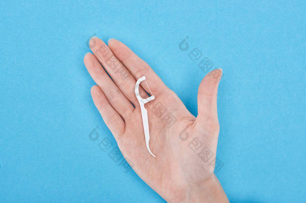 裁剪视图的妇女拿着白色牙线牙签在蓝色手 