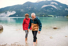 一对年迈的退休夫妇赤脚徒步在自然界的湖中远足.