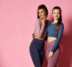 两个运动女孩国际朋友在现代高科技五颜六色的运动服上摆出粉红色