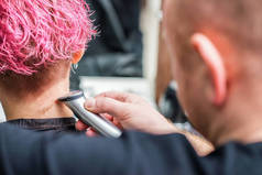 美容院里，理发师用电动剃须刀把妇女的头发剃光.