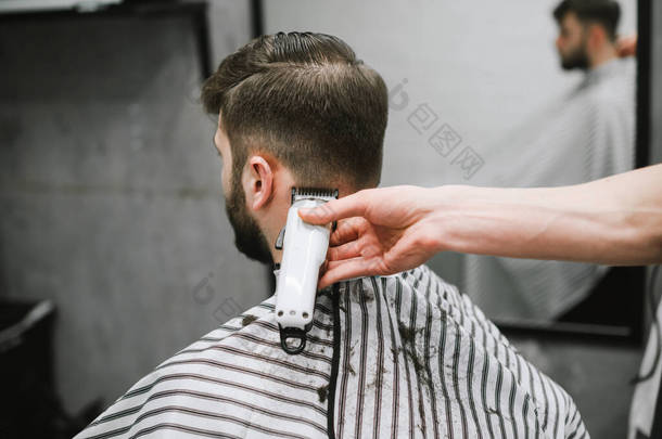 近照理发师音乐会理发师的手与剪子剪短了长胡子的成年男子的头发，黑头发，后视镜。男理发师的工作。背景