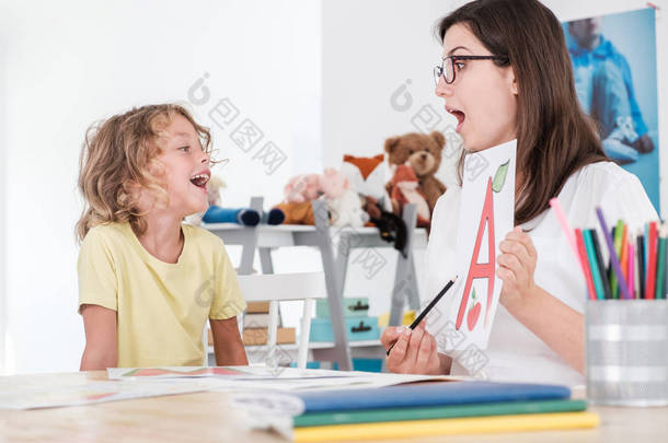 一个快乐的孩子在语音治疗与专家发音.