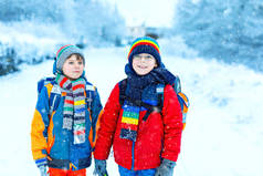 下大雪时，两个小学的小男孩步行去学校。快乐的孩子们玩的开心，玩的是初雪。姐姐们的朋友们，背着五颜六色的冬衣背包.