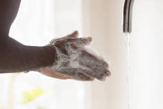 年轻的非洲裔美国人用泡沫抗菌肥皂洗手.