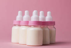 婴儿奶瓶充满牛奶在粉红色的背景