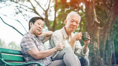 亚洲高级情侣在夏季公园放松饮用咖啡, 绿色 