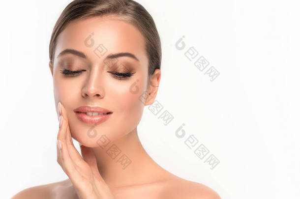 美丽的年轻女子，洁白清新的肌肤触摸着自己的脸。<strong>面部治疗</strong>。化妆品、美容美发和温泉 