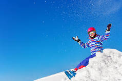 一个穿着五颜六色滑雪服的漂亮姑娘的画像，举手投足，在蓝天上空飞雪