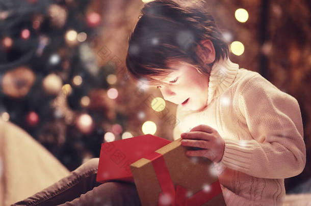 圣诞前夕在壁炉前的家人。孩子们打开圣诞礼物。圣诞树下的孩子们带着礼品盒。用传统的壁炉装饰客厅。温暖温暖的冬夜回家.