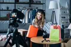 微笑的时尚博客坐在购物袋和录制新的视频网 