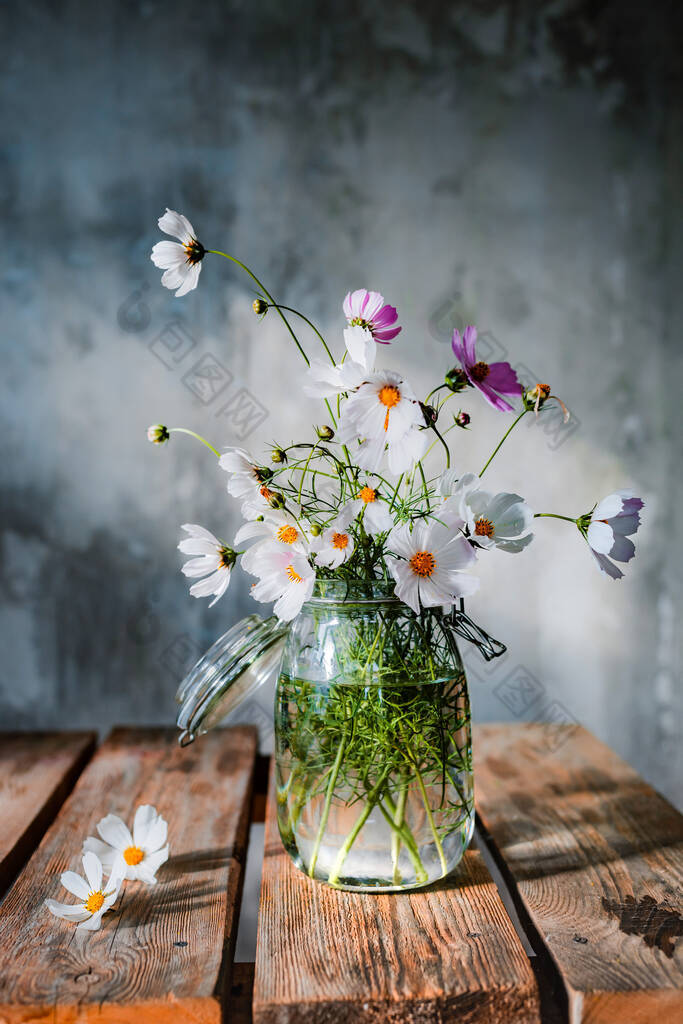 美丽的野花花束在木制桌子上，冷冰冰的混凝土墙背景上。花匠以乡村风格简单地布置花束。自由空间