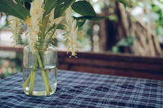 玻璃瓶中的白花绿叶装饰在家里的桌子上