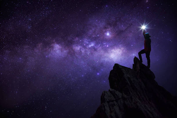 登山者或背包客的剪影, 他把明星高高举起头顶。站在岩石山峰上对抗银河系, 恒星和太空尘埃在宇宙中, 成功, <strong>领导</strong>概念.