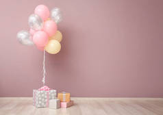 粉红色墙壁附近五颜六色的气球和礼品盒