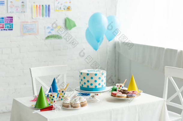 节日蛋糕和*帽在房间里装饰与气球生日派对