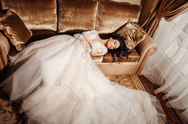 时尚照片美丽的新娘与长的黑发在豪华的<strong>婚纱礼服</strong>和配件摆在优雅的内饰
