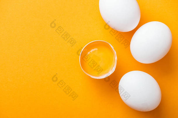 在白色整个鸡<strong>蛋</strong>中, 在明亮的橙色<strong>背景</strong>上, 用<strong>蛋</strong>黄<strong>砸</strong>碎的鸡<strong>蛋</strong>的顶部视图