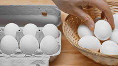 从木桌上靠近蛋盘的柳条筐里取出鸡蛋的人的剪影