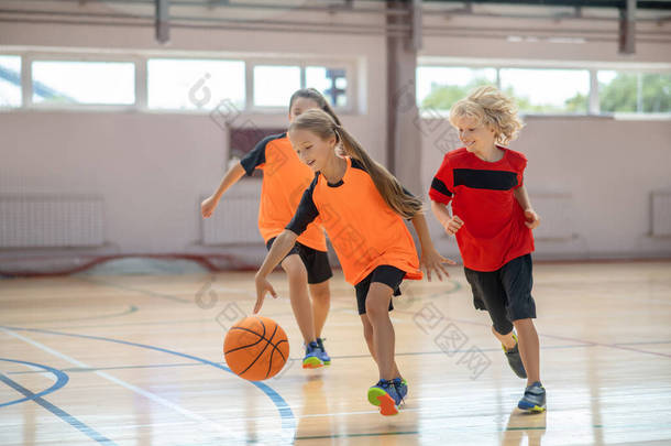 穿着鲜艳运动服的孩子们打篮球，看起来很兴奋