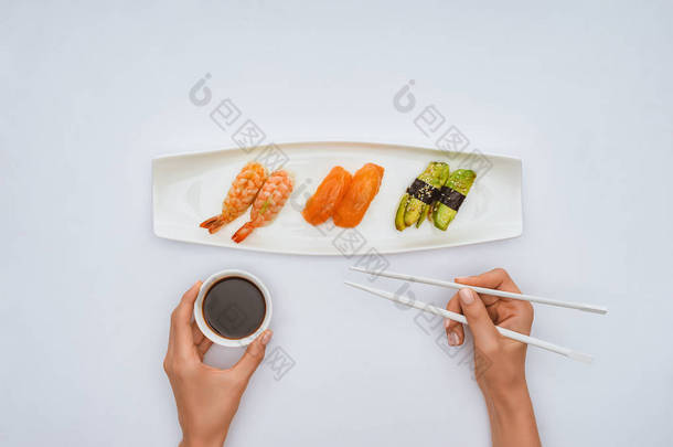 手持筷子和碗<strong>酱油</strong>的人在吃白色的<strong>寿司</strong>时被裁剪的镜头
