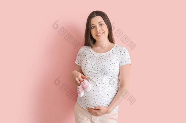 漂亮的孕妇，穿着彩色背景的婴儿鞋