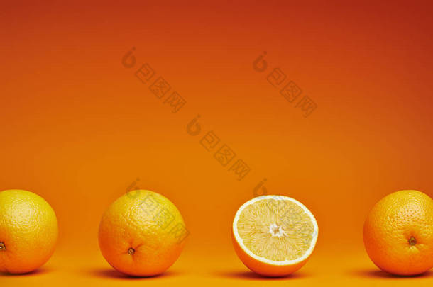 新鲜成熟的<strong>整体</strong>特写镜头视图和橙色背景上的一半橙子 