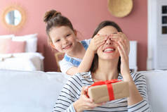 小女孩给兴奋的父母做生日礼物，笑着的小孩祝贺送给快乐的母亲礼品盒和闭着的母亲的眼睛