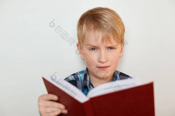 人脸表情和情绪。儿童和教育。有吸引力的小男孩，用公平的头发看书<strong>已经</strong>厌倦了作业有愤怒的表情的特写镜头。无聊的学校研究