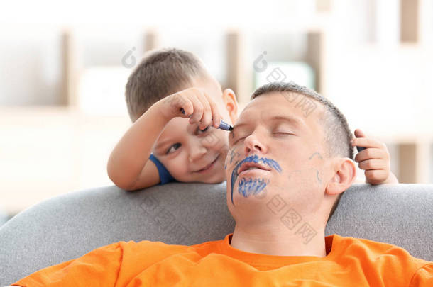小男孩在他睡觉的时候画他父亲的脸。愚人节恶作剧