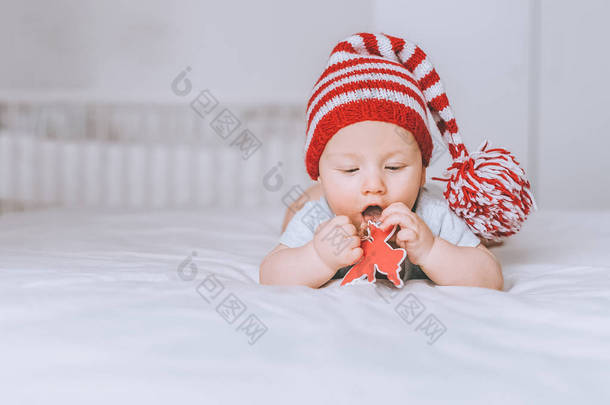 婴儿在<strong>红色</strong>和白色条纹帽与绒球玩玩具天使在床上