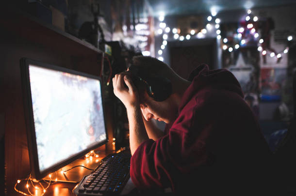 沮丧的玩家的肖像与他的被击倒的手在游戏中输球。沮丧的少年坐在电脑桌前, 很难过。因为失望, 玩家失败了.