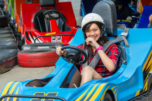 可爱亚洲泰国女孩带着笑脸的乐趣从操场上赛车中的起始点与速度驾驶<strong>卡丁车</strong>时跟踪。<strong>卡丁车</strong>是受欢迎的休闲赛车运动.