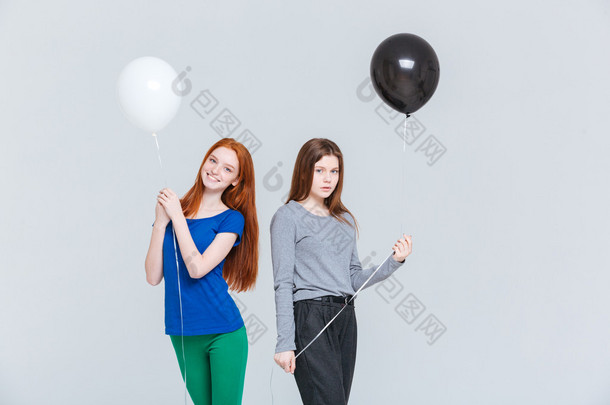两个年轻妇女抱着黑色和白色的气球