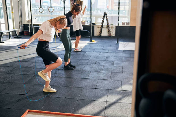微笑的女士们在<strong>体育馆</strong>里用跳绳锻炼