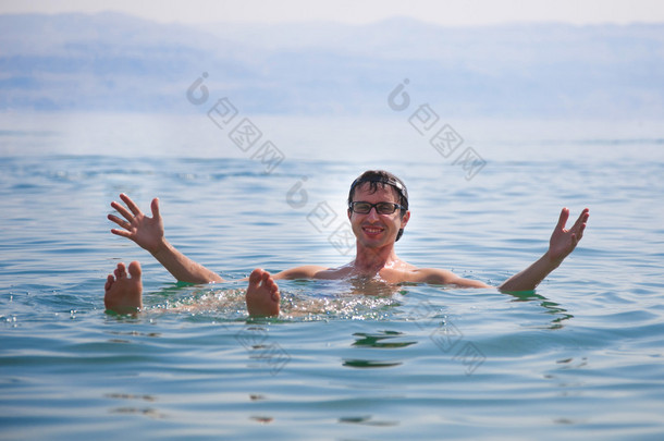 一个人在于他的手上在以色列死海的水