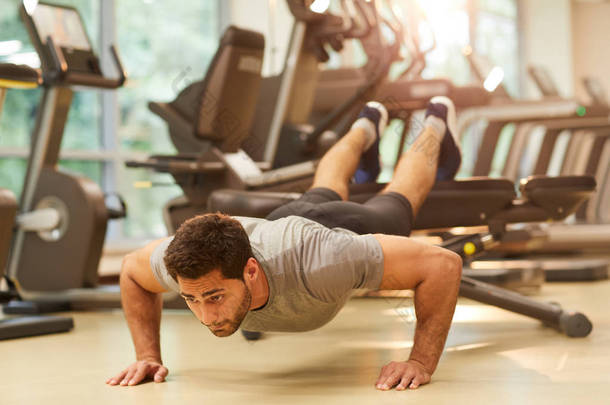 在健身房锻炼期间，肌肉男子在长凳上做俯卧撑的全长肖像，复制空间