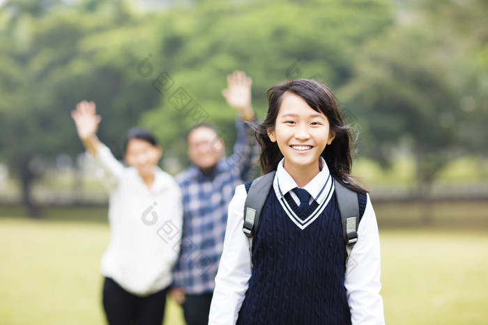 可爱的年轻学生女孩与家长在学校