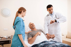 那位老人躺在医务室的一张小床上。他旁边是医生和护士.