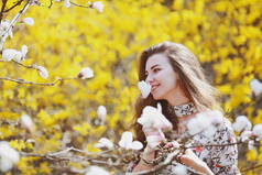 美丽的年轻女子在花园里嗅着一棵开花的树