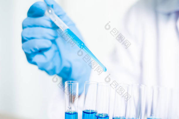 医学科学家在一个化学实验室将一个样本管道释放到试管中，以分析病毒。科学研究概念.