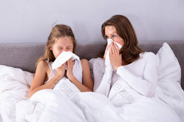母亲和女儿因冷爆在床上用手帕吹鼻子而痛苦