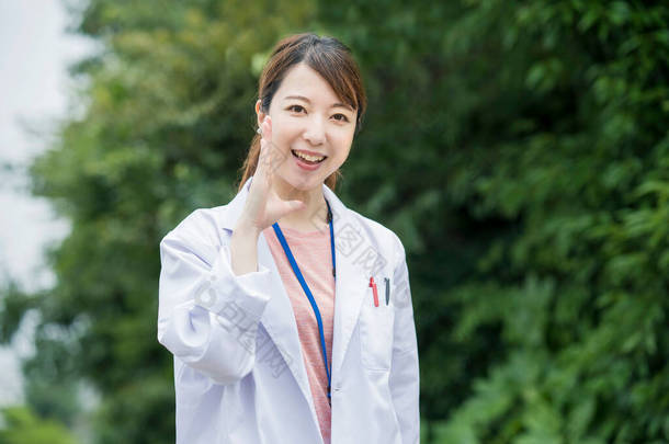 身穿白衣、摆出室外姿势的亚洲女保健工作者
