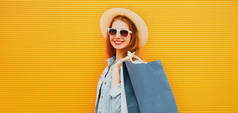 微笑的年轻女子提着购物袋走在城市的橙色背景下