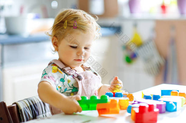 可爱的蹒跚学步的小女孩在<strong>幼儿园</strong>玩教育玩具。快乐健康的孩子在家里用五颜六色的塑料块玩乐.可爱的婴儿学习创造和建设.
