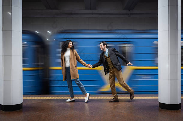地铁中手牵着手在马车附近行走的互动伴侣的运动模糊