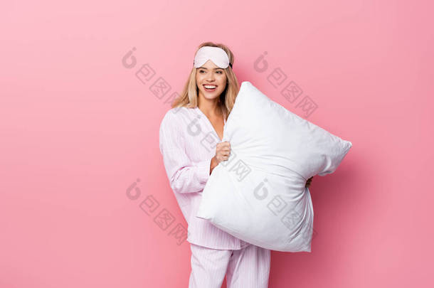 身穿睡衣、头戴眼罩、头戴粉色背景白色枕头的年轻女子